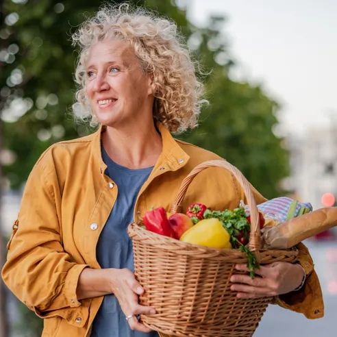 Smiling woman carrying a basket of fresh vegetables
